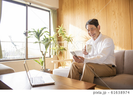 リビングでスマホでネットを見るミドル〜シニア男性 リビングでスマホでネットを見るミドル〜シニア男性 61638974