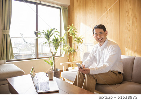 リビングでスマホでネットを見るミドル〜シニア男性 リビングでスマホでネットを見るミドル〜シニア男性 61638975