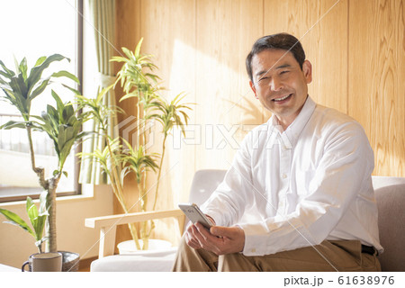 リビングでスマホでネットを見るミドル〜シニア男性 61638976