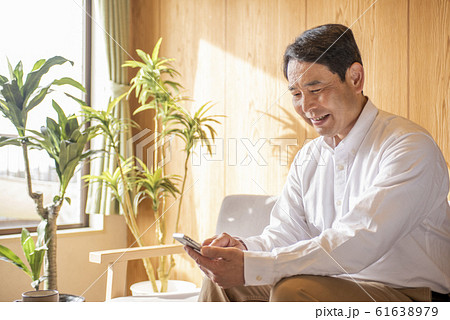 リビングでスマホでネットを見るミドル〜シニア男性 リビングでスマホでネットを見るミドル〜シニア男性 61638979