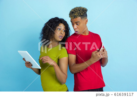 Young emotional african-american man and woman on blue background Young emotional african-american man and woman on blue background 61639117