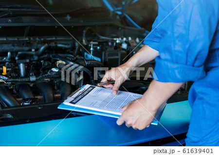 Car mechanic holding clipboard and checking to Car mechanic holding clipboard and checking to 61639401