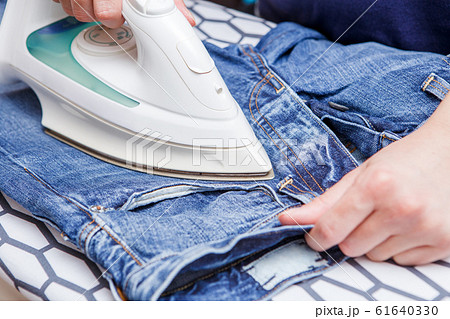 Image of man ironing jeans 61640330