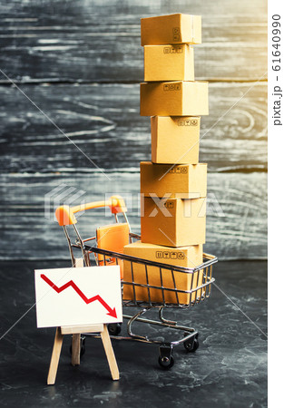 Shopping cart filled with boxes and a stand sign with a red down arrow. decline in the production of goods, Falling consumer demand. The fall in sales and consumer sentiment due to the economy crisis. 61640990