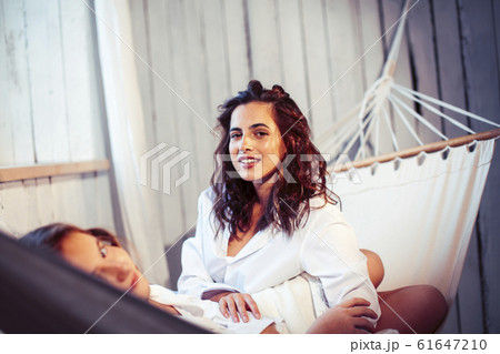 young pretty sisters at home early morning in hammock, lifestyle casual people concept young pretty sisters at home early morning in hammock, lifestyle casual people concept 61647210