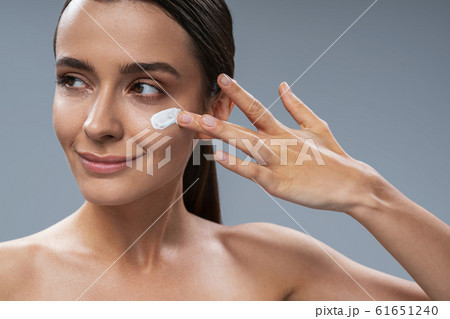 Charming tender girl taking care of facial skin against grey background 61651240