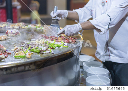 A cook in a restaurant fries food on a large iron A cook in a restaurant fries food on a large iron 61655646