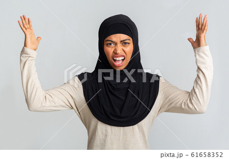 Angry black muslim girl shouting and raising hands in fury Angry black muslim girl shouting and raising hands in fury 61658352