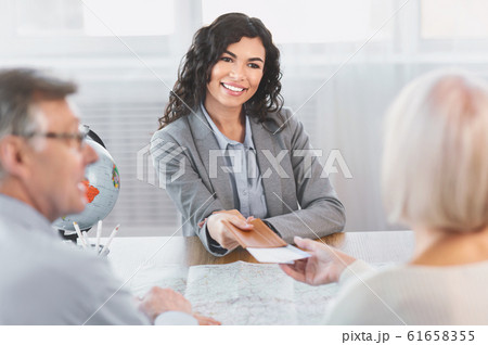 Woman giving tickets to happy mature couple Woman giving tickets to happy mature couple 61658355