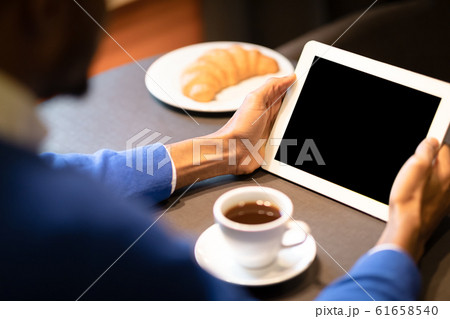 Black man with tablet reading news in cafe shop 61658540