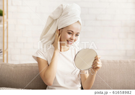 Girl looking at mirror, wearing towel on head after shower 61658982