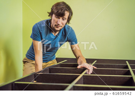 Frustrated Man Putting Together Self Assembly Furniture Frustrated Man Putting Together Self Assembly Furniture 61659542
