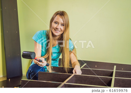 Caucasian woman using screwdriver for assembling furniture 61659976
