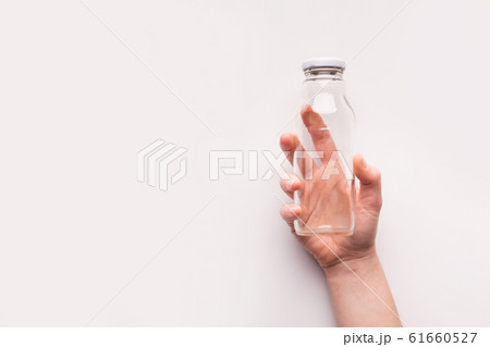 Empty Glass bottle in woman hand on white background Empty Glass bottle in woman hand on white background 61660527