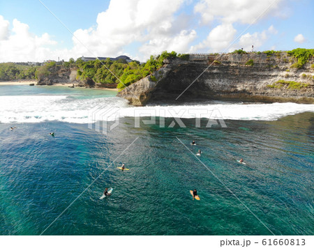 Aerial view of surfer on their board waiting the waves next the cliff, Bali 61660813