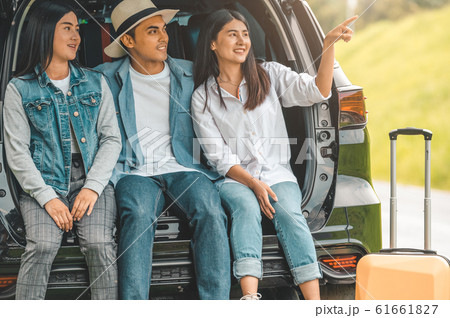 Asian man and women relaxing in back of car trunk 61661827