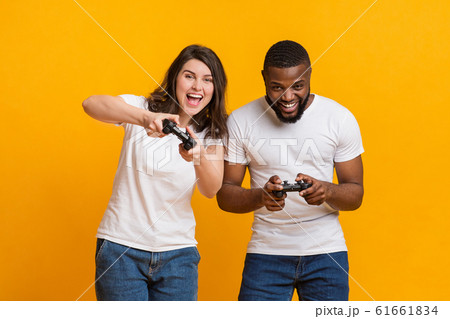 Joyful interracial couple holding joysticks competing each other in video games 61661834