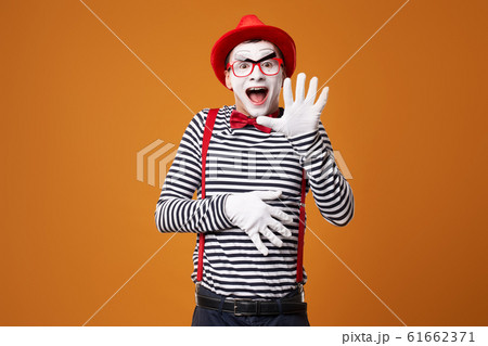 Happy mime in vest and red hat on orange background Happy mime in vest and red hat on orange background 61662371