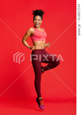 Cheerful fitness girl exercising over red background 61662534