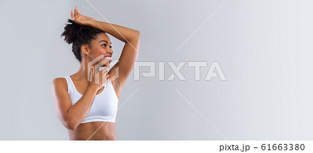 Cheerful black girl smelling her armpit over grey background Cheerful black girl smelling her armpit over grey background 61663380