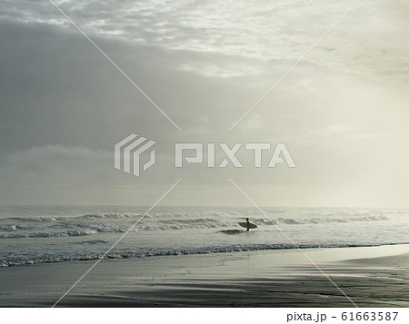 潮見坂海岸にて台風接近の荒波に一人でサーフィンする若者 61663587
