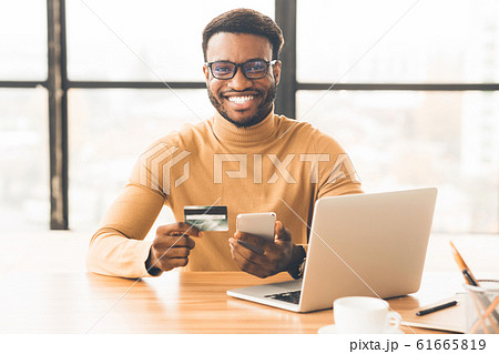 Afro manager making purchases using laptop computer Afro manager making purchases using laptop computer 61665819