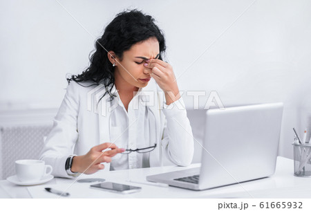 Tired mexican teacher massaging nose and eyes Tired mexican teacher massaging nose and eyes 61665932