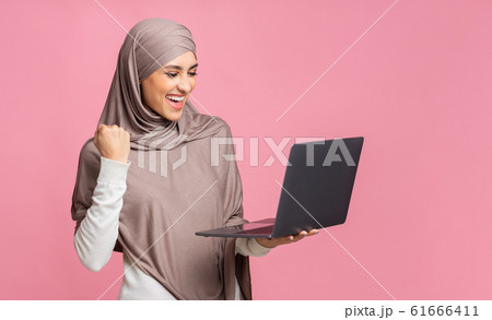 Euphoric Arabic Girl In Hijab Celebrating Success With Laptop Euphoric Arabic Girl In Hijab Celebrating Success With Laptop 61666411
