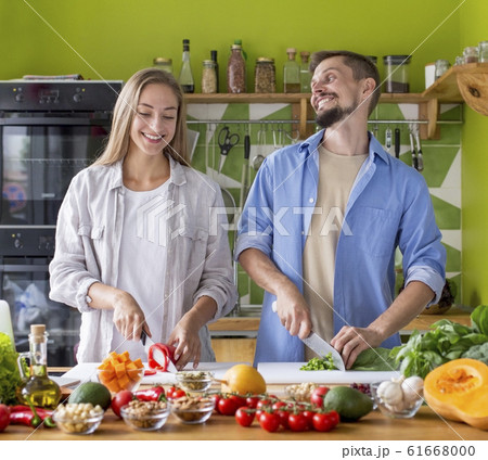 Happy just married couple in aprons chopping vegetables 61668000
