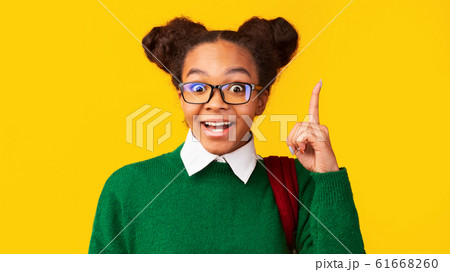 Afro teenager pointing up over yellow studio wall 61668260
