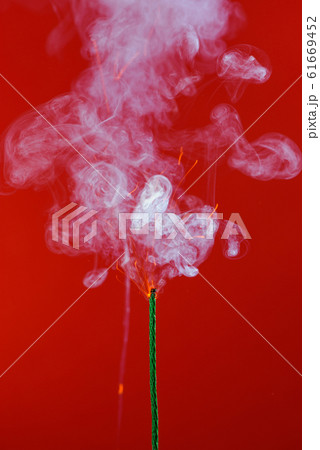 Burning fuse wick with sparks and smoke on red background 61669452