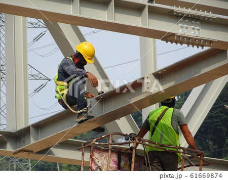 Construction workers working at height installing the steel structure. Steel structure able to provide huge and long span for the building. Construction workers working at height installing the steel structure. Steel structure able to provide huge and long span for the building. 61669874