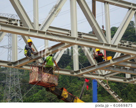 Construction workers working at height installing the steel structure. Steel structure able to provide huge and long span for the building. Construction workers working at height installing the steel structure. Steel structure able to provide huge and long span for the building. 61669875