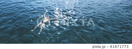 Young woman in swimwear lying on blue water, aerial view 61671773