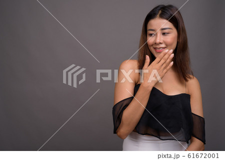 Young beautiful Asian woman against gray background Young beautiful Asian woman against gray background 61672001