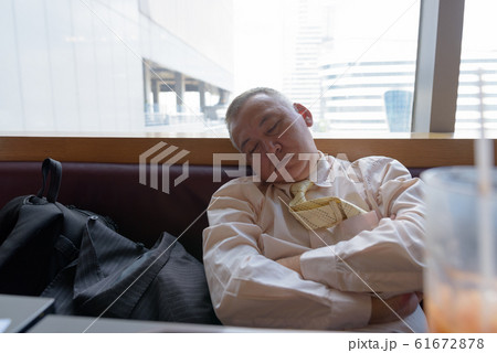 Mature Asian businessman relaxing inside the restaurant Mature Asian businessman relaxing inside the restaurant 61672878