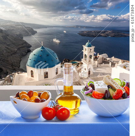 Greek salad against famous church in Thira town on Santorini island in Greece 61673804
