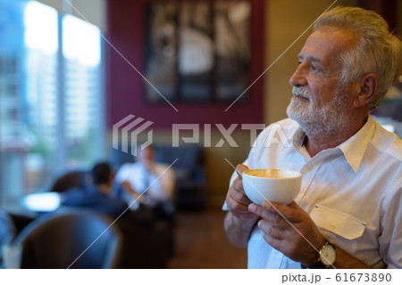 Handsome senior tourist man relaxing inside the coffee shop 61673890