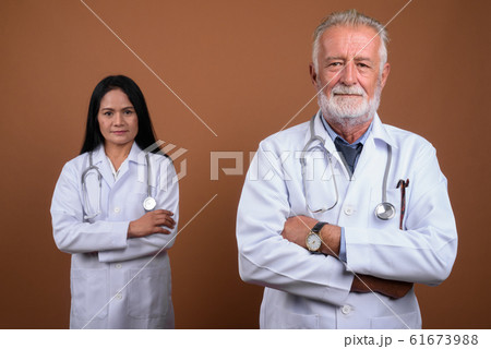 Mature multi-ethnic couple doctors against brown background 61673988