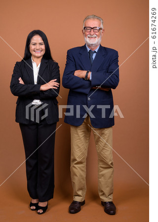 Mature multi-ethnic business couple against brown background 61674269