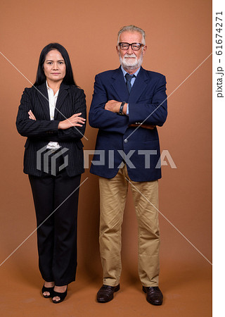 Mature multi-ethnic business couple against brown background Mature multi-ethnic business couple against brown background 61674271