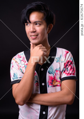 Young handsome Asian man against black background 61675674