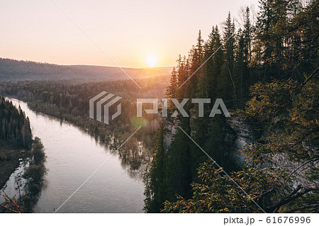 Scenic landscape, man on on edge of cliff meeting beutiful sunrise over mountain river with raised hands 61676996