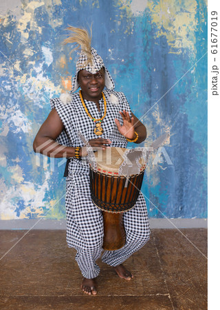 African artist in traditional clothes playing djembe drum African artist in traditional clothes playing djembe drum 61677019