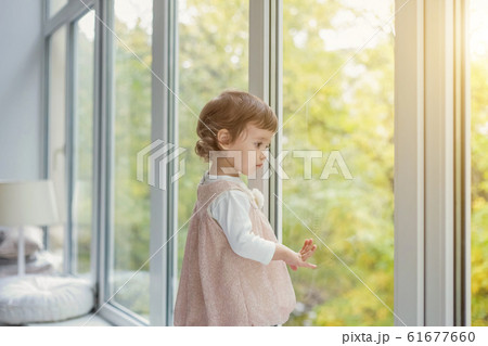Little girl standing on window sill Little girl standing on window sill 61677660