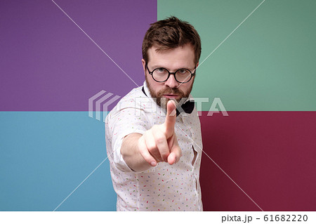 Stern man with round glasses makes a stop gesture with index finger, tries to calm someone and looks Stern man with round glasses makes a stop gesture with index finger, tries to calm someone and looks 61682220