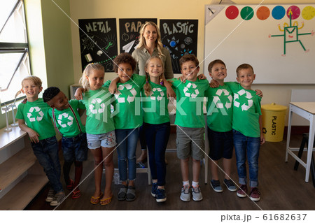 Female school teacher with a group of schoolchildren wearing green t shirts with a white recycling l Female school teacher with a group of schoolchildren wearing green t shirts with a white recycling l 61682637