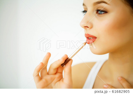 Beauty and Care. Portrait of a Young Woman with a Beautiful Skin. Beautiful Lips. Girl Holding Lipstick in her Hands. Woman with Beautiful Blue Eyes. Makeup. Care for the Lips Beauty and Care. Portrait of a Young Woman with a Beautiful Skin. Beautiful Lips. Girl Holding Lipstick in her Hands. Woman with Beautiful Blue Eyes. Makeup. Care for the Lips 61682905
