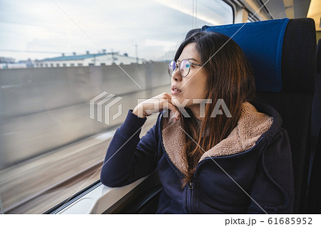Asian Young lady passenger Sitting in a depressed mood beside the window inside Train which travel between town when travel alone for escape the chaos, traveller and depress concept Asian Young lady passenger Sitting in a depressed mood beside the window inside Train which travel between town when travel alone for escape the chaos, traveller and depress concept 61685952