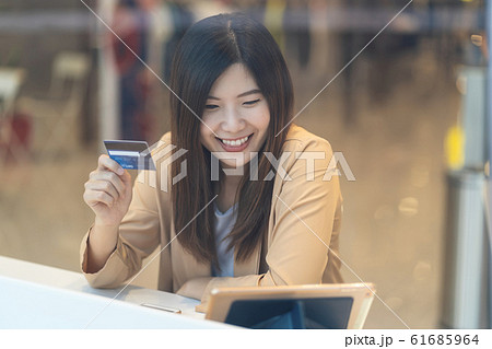 Asian woman using credit card with mobile phone for online shopping in department store over the clothes shop store background, technology money wallet and online payment concept, credit card mockup Asian woman using credit card with mobile phone for online shopping in department store over the clothes shop store background, technology money wallet and online payment concept, credit card mockup 61685964